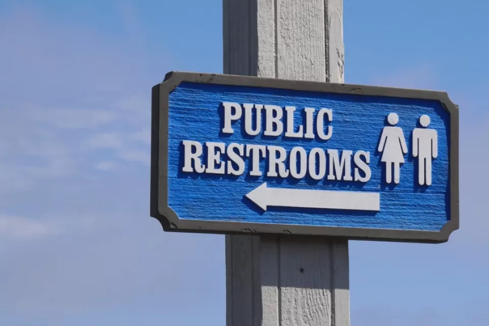 Blue "Public Restrooms" sign with arrow against a blue sky